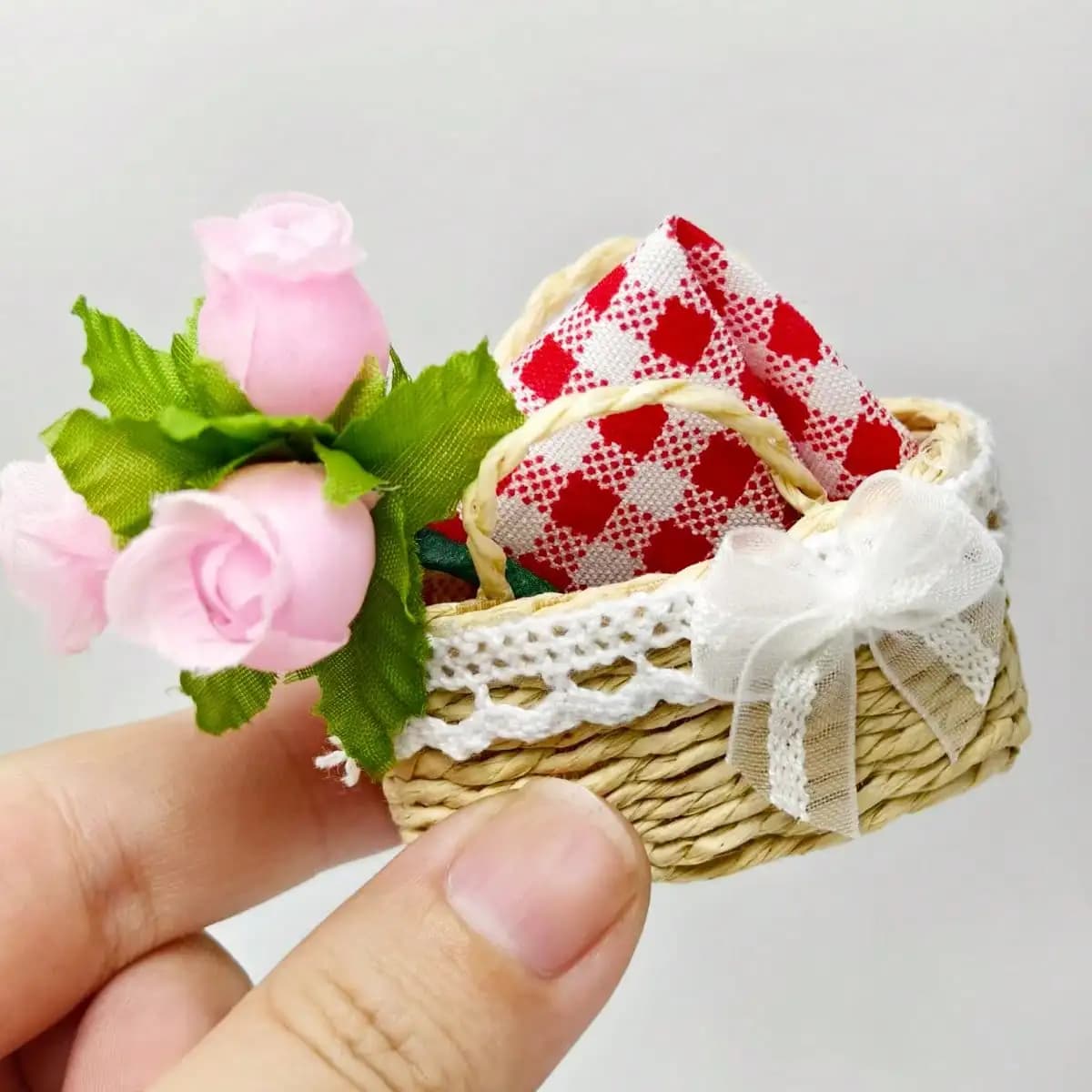 Panier de pique-nique miniature artisanal en paille avec nappe à carreaux, orné d'un nœud en dentell